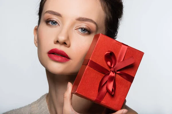 Portrait of young woman holding present and looking at camera isolated on white — Stock Photo