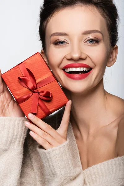 Retrato de mujer alegre en suéter caliente sosteniendo presente aislado en blanco - foto de stock