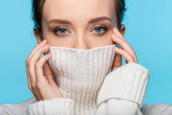 Young woman covering face with warm sweater isolated on blue — Stock Photo