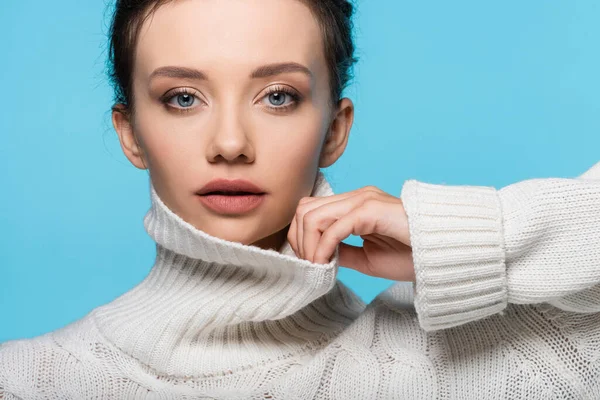 Giovane modello toccante colletto di maglia maglione isolato su blu — Foto stock