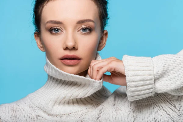 Junges Model berührt Kragen von Strickpullover isoliert auf blau — Stockfoto