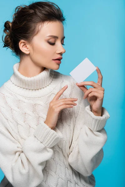 Brünette Frau im Strickpullover mit weißer Blanko-Karte auf blauem Hintergrund — Stockfoto