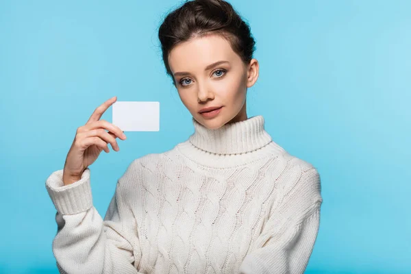 Model in white sweater holding blank card isolated on blue — Stock Photo