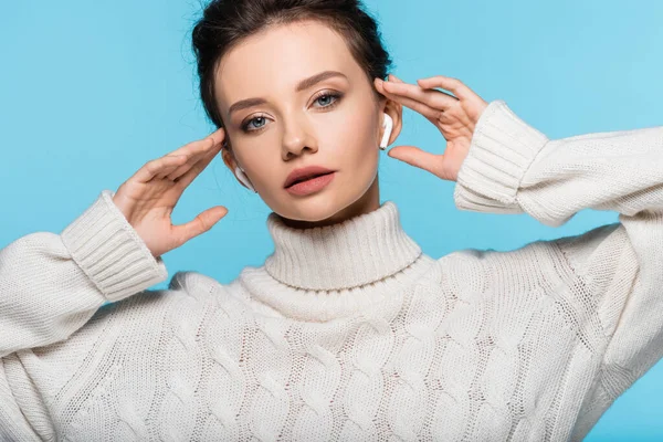 Bella donna in maglia maglione utilizzando auricolari isolati su blu — Foto stock