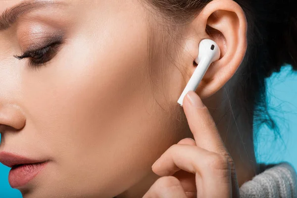 Cropped view of woman using wireless earphone isolated on blue — Stock Photo
