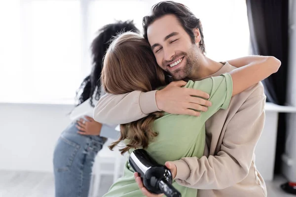 Happy man with bottle of wine hugging friend at home — Stock Photo