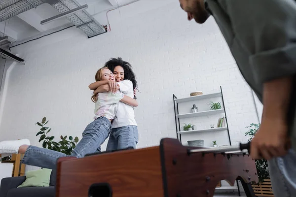 Vista de ángulo bajo de feliz pareja lesbiana abrazándose cerca de hombre - foto de stock