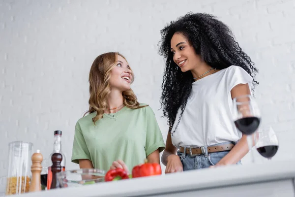 Low angle view of happy interracial lesbian couple cooking in kitchen — Stock Photo