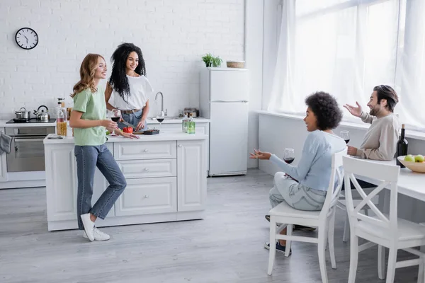 Cheerful multiethnic friends talking in modern kitchen — Stock Photo