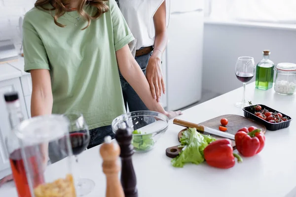 Vista cortada de jovens casal do mesmo sexo em pé perto de legumes na cozinha — Fotografia de Stock