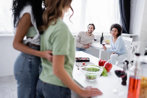 Happy interracial man and woman looking at blurred same sex couple — Stock Photo