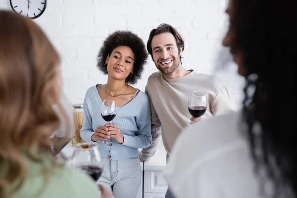 Happy multiethnic couple looking at lesbian women on blurred foreground — Stock Photo