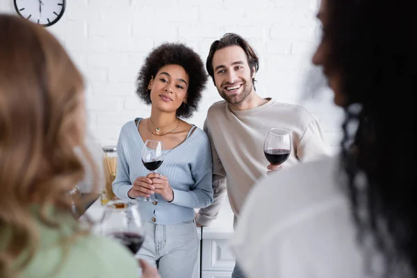 Glückliches multiethnisches Paar, das lesbische Frauen im verschwommenen Vordergrund betrachtet — Stockfoto