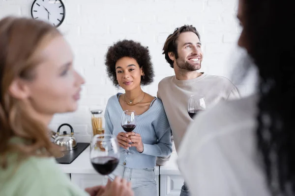 Glückliches multiethnisches Paar in der Nähe lesbischer Frauen im verschwommenen Vordergrund — Stockfoto