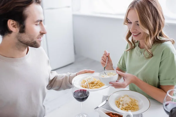 Woman holding bowl with grated cheese near man holding plate with pasta — Stock Photo