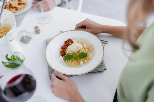 High angle view of pasta bolognese with grated cheese on plate near woman — Stock Photo