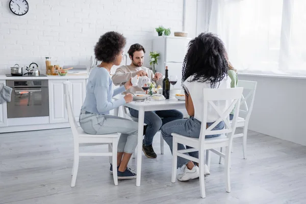 Amigos multiétnicos comiendo pasta durante el almuerzo - foto de stock