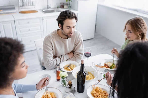 Vista de ángulo alto del hombre almorzando con mujeres multiétnicas - foto de stock