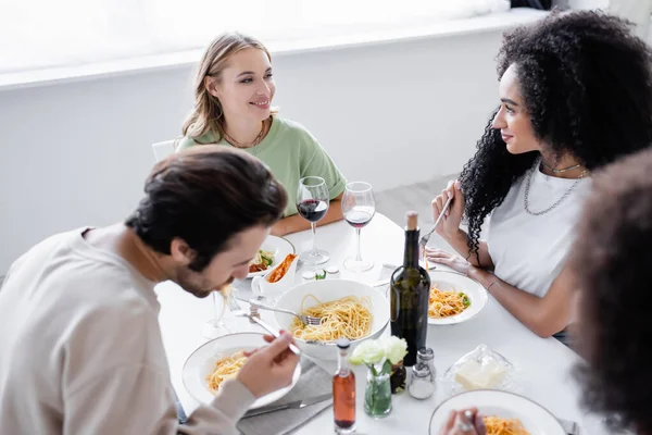 Веселі багатоетнічні лесбіянки дивляться один на одного біля друзів, обідаючи — стокове фото