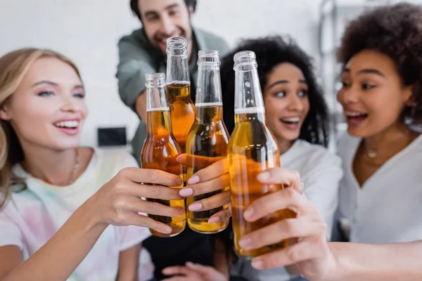 Blurred and happy interracial group of friends clinking bottles of beer — Stock Photo