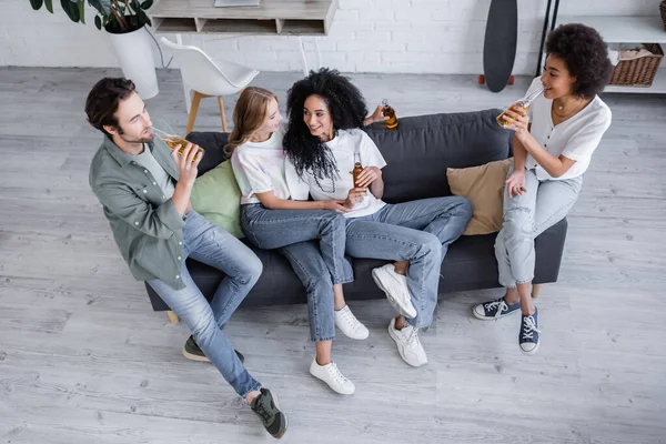 High angle view of happy lesbian couple sitting on couch with interracial friends with beer — Stock Photo
