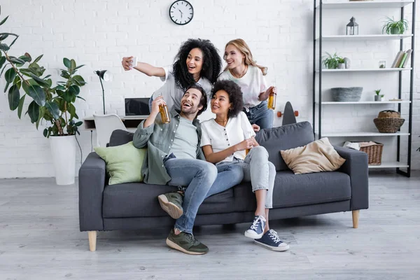 Feliz afro-americana tomando selfie com amigos na sala de estar — Fotografia de Stock