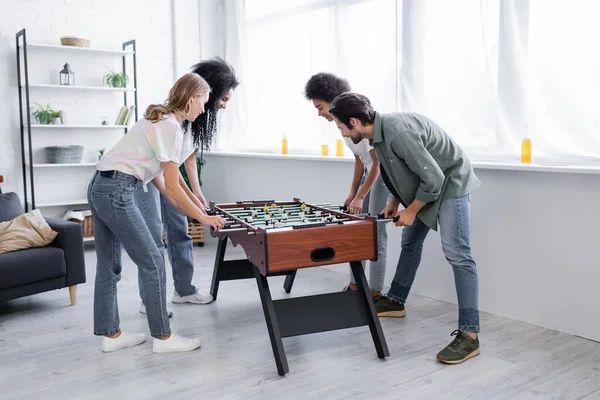 Feliz interracial las mujeres y el hombre jugando futbolín - foto de stock