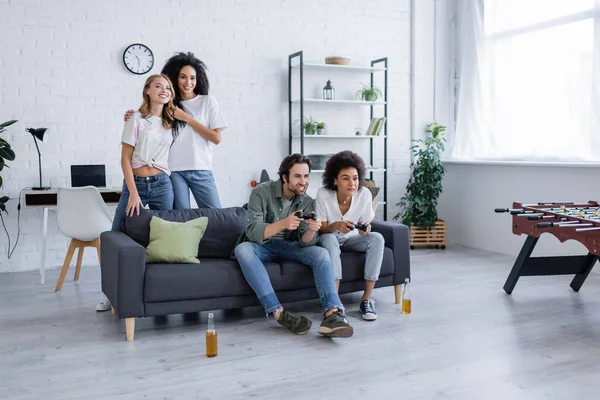 KYIV, UKRAINE - OCTOBER 7, 2021: tensed multiethnic friends playing video game near cheerful lesbian couple — Stock Photo