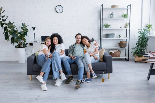 Cheerful lesbian and heterosexual couples watching movie on sofa — Stock Photo