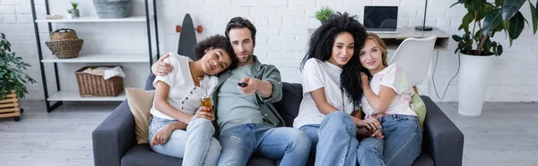 Веселые лесбийские и гетеросексуальные пары смотрят кино на диване, баннере — стоковое фото