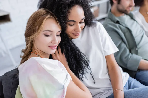 Cheerful lesbian couple near blurred friends — Stock Photo