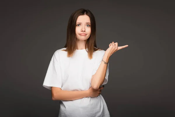 Femme découragée regardant caméra et pointant du doigt isolé sur gris foncé — Photo de stock
