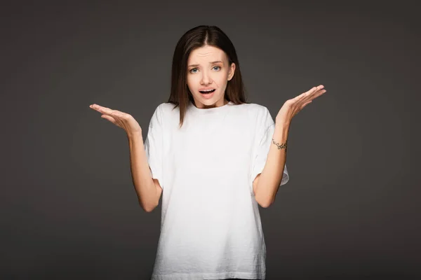 Irritated woman showing indignant gesture while looking at camera isolated on dark grey — Stock Photo