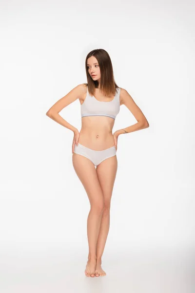 Full length view of barefoot woman in underwear standing with hands on hips on white background — Stock Photo
