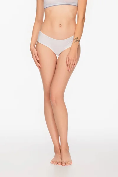 Abgeschnittene Ansicht einer barfüßigen Frau mit schlanken Beinen auf weißem Hintergrund — Stockfoto