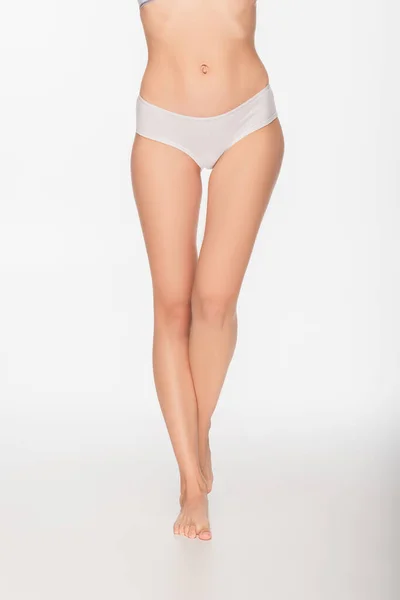 Vista parcial de mujer con piernas delgadas y lisas sobre fondo blanco - foto de stock