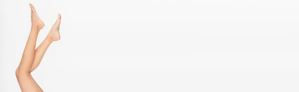 Обрезанный вид узких босых ног молодой женщины, изолированных на белом, баннер — стоковое фото