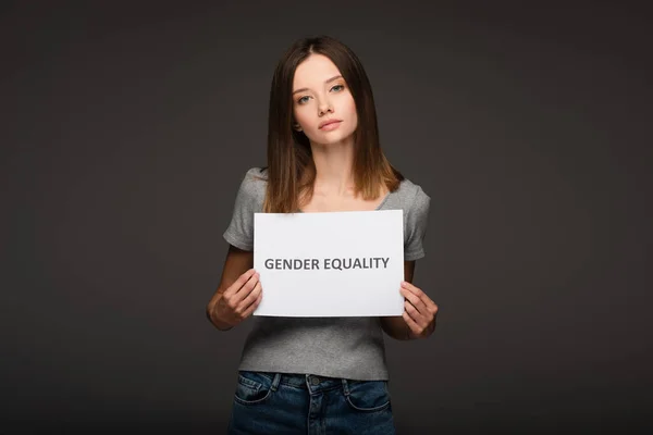 Young brunette woman holding placard with gender equality inscription isolated on grey — Stock Photo