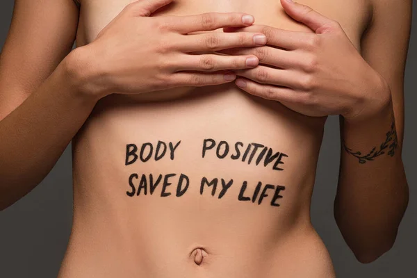 Cropped view of nude woman with body positive saved my life inscription on body isolated on dark grey — Stock Photo