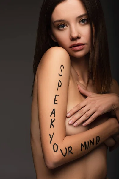 Mujer desnuda con hablar su letra mente en el brazo mirando a la cámara aislada en gris oscuro - foto de stock