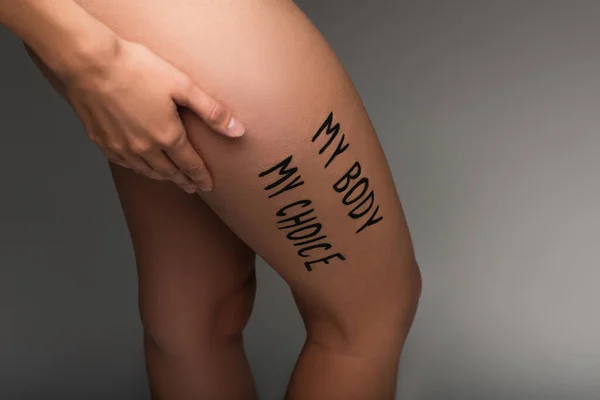 Cropped view of nude woman with my body my choice lettering on hip isolated on dark grey — Stock Photo