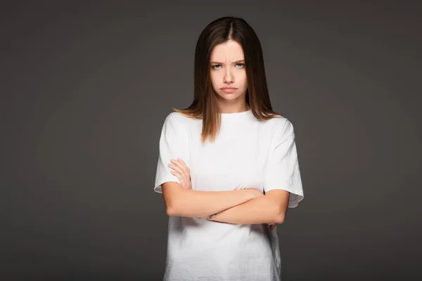 Offended woman standing with crossed arms while looking at camera isolated on dark grey — Stock Photo
