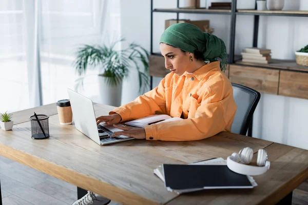 Arabian woman in headkerchief typing on laptop while learning at home — Stock Photo
