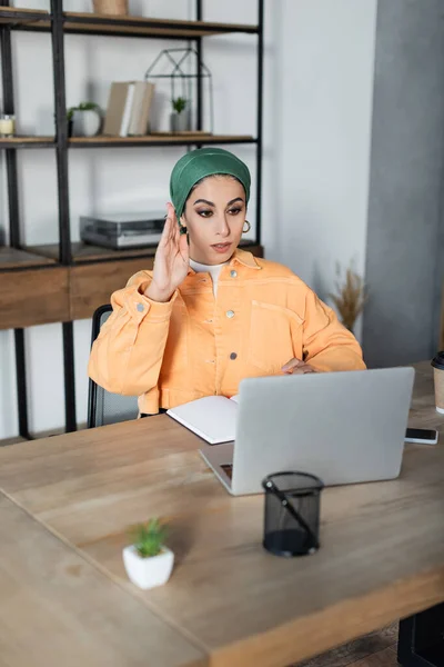 Muslim woman raising hand during online lesson at home — Stock Photo