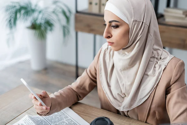 Mulher de negócios muçulmana usando smartphone enquanto trabalhava em casa — Fotografia de Stock