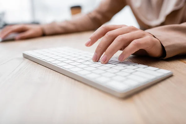 Vista parcial de la mujer escribiendo en el teclado mientras trabaja en casa - foto de stock