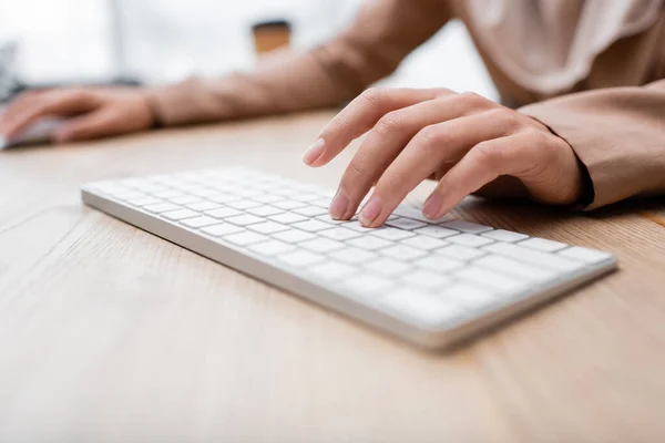 Vue partielle de la femme tapant sur le clavier tout en travaillant à la maison — Photo de stock