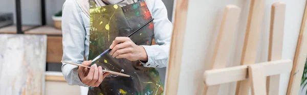 Vue partielle de l'artiste avec palette et pinceau près du chevalet, bannière — Photo de stock