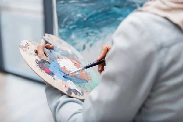 Partial view of woman with paintbrush near blurred picture — Stock Photo