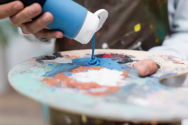 Vista recortada de la mujer exprimiendo pintura en la paleta - foto de stock